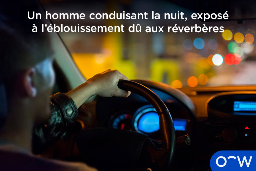 Un homme conduisant la nuit, exposé à l'éblouissement dû aux réverbères.