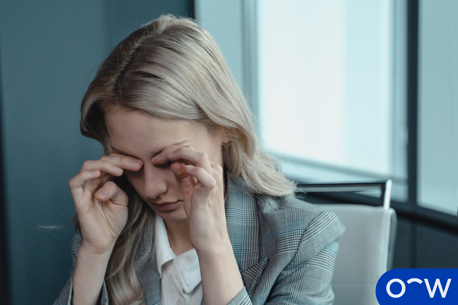 Une femme portant ses doigts à ses yeux.