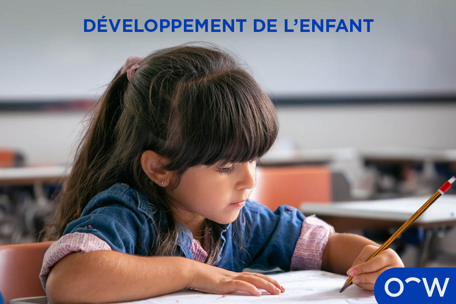 Un enfant dans une classe, assis sur une chaise et faisant ses devoirs.