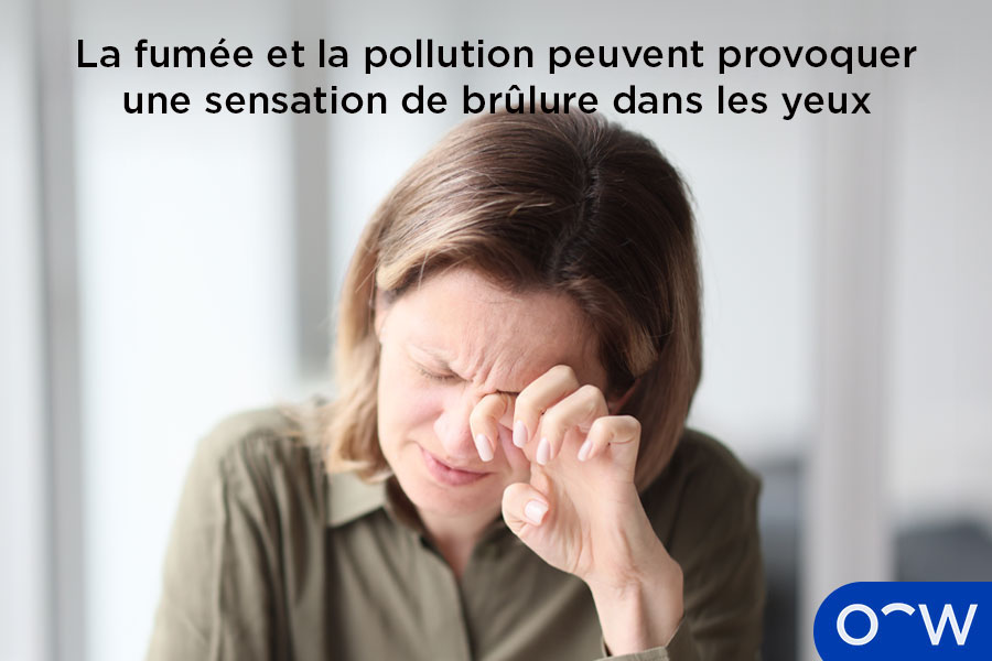 Une femme couvrant ses yeux irrités qui brûlent à cause de la fumée et de la pollution.