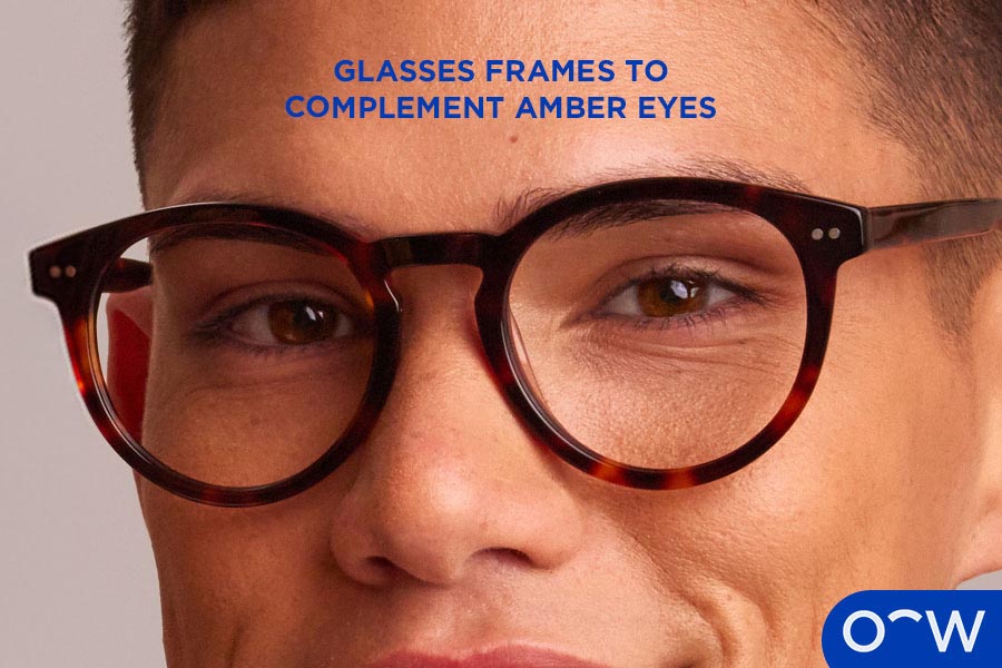 A man smiling, wearing tortoiseshell glasses.