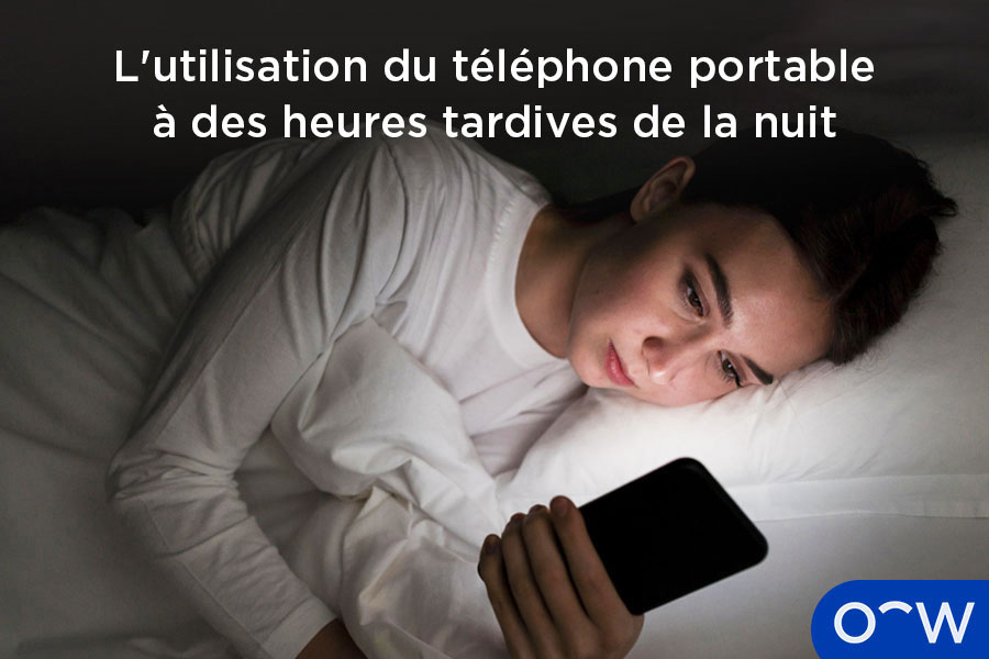 Une femme dans son lit qui utilise son smartphone et ressent une douleur oculaire.