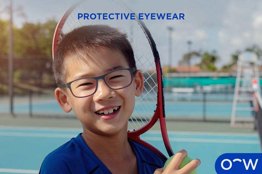 Child wearing protective eyewear and holding a tennis racket.