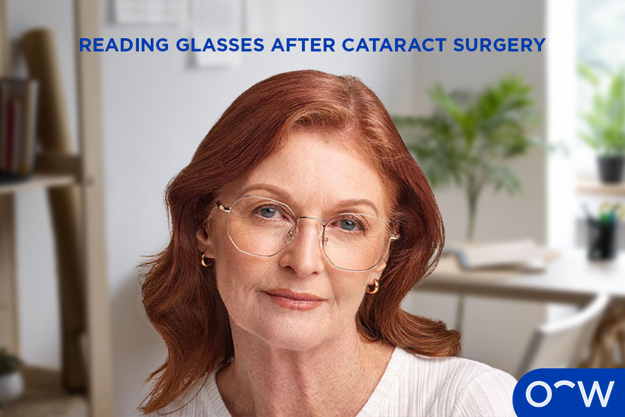 A close up of a woman smiling at the camera wearing round reading glasses.