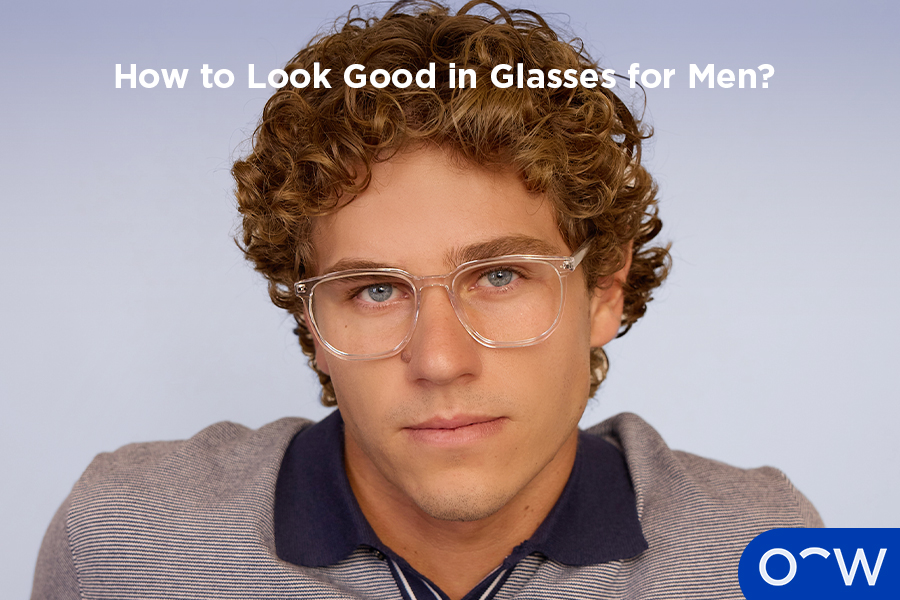 A man posing to the side, wearing clear glasses